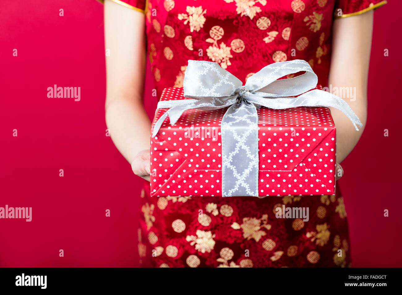 young woman holding gift box on red background Stock Photo
