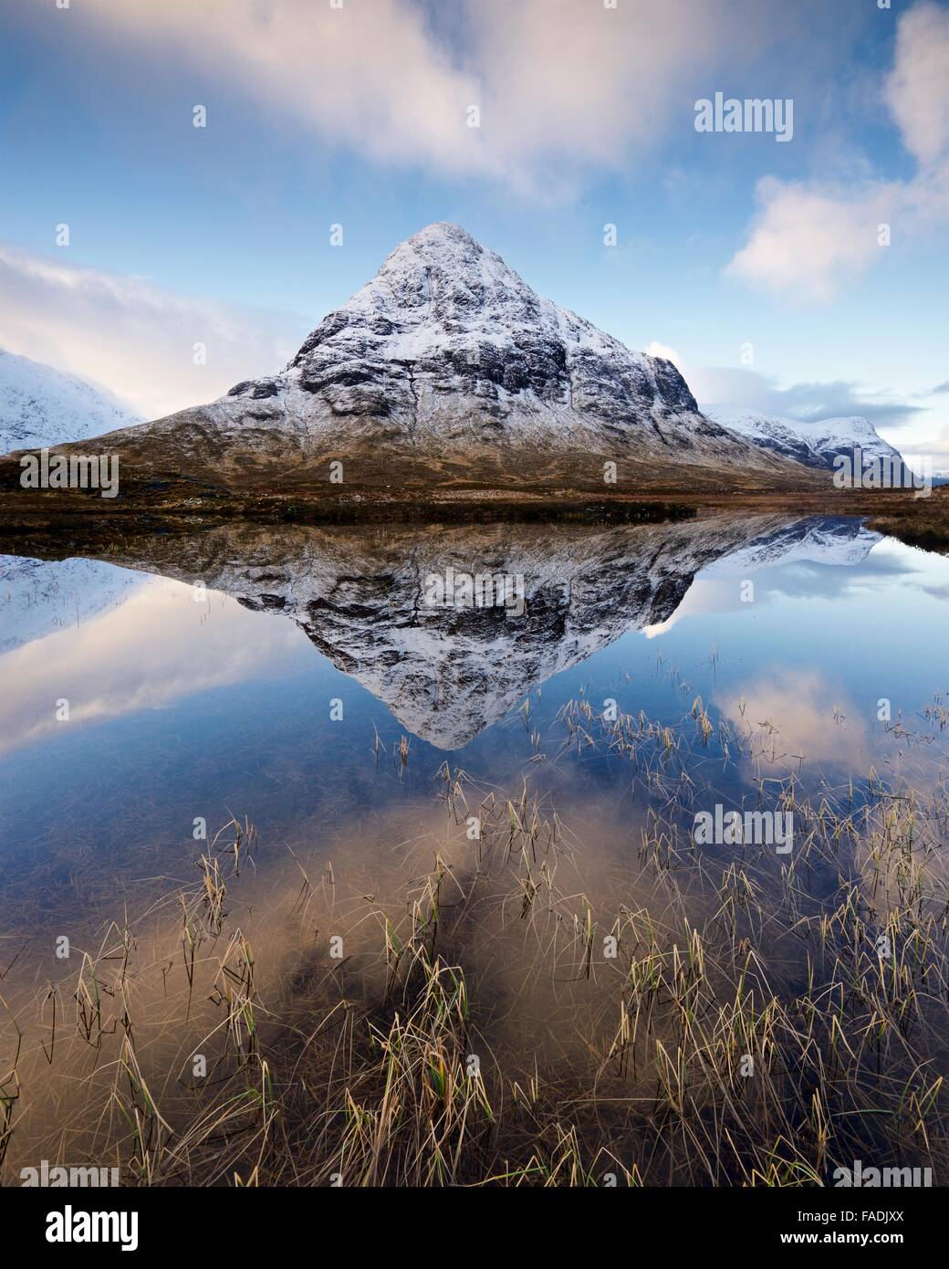 A colour image taken of the snow covered landscape reflected into a still Lochan Na Fola in Glencoe, Scotland Stock Photo