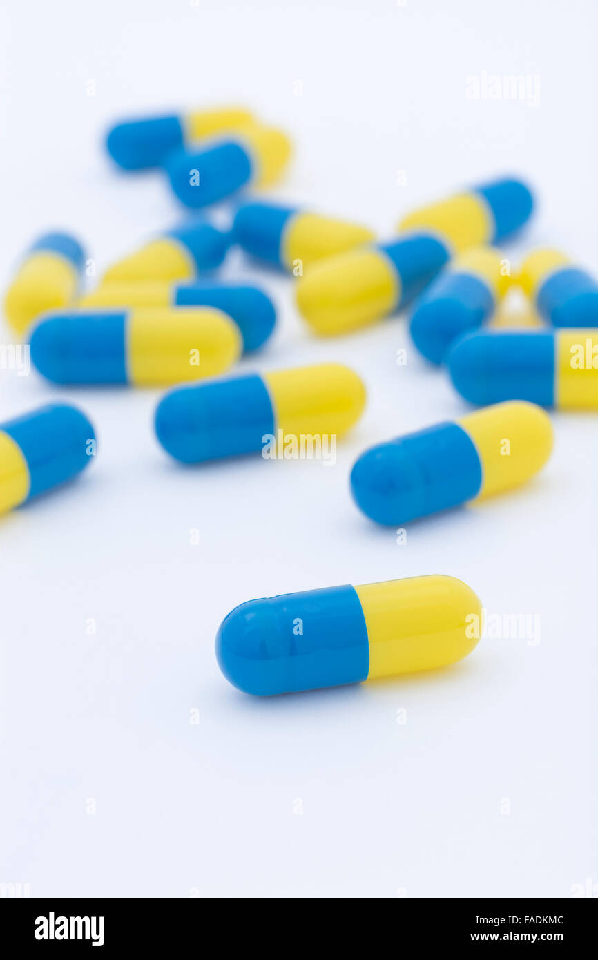 Close-up of blue and yellow pills - capsule form made of gelatin. Big Pharma concept, drug trials. Stock Photo