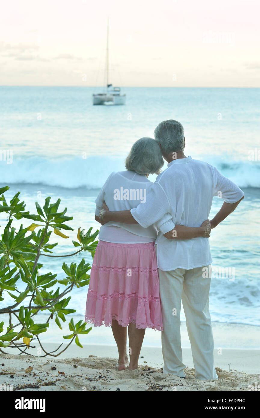 Elderly couple on the beach facing the sea Stock Photo