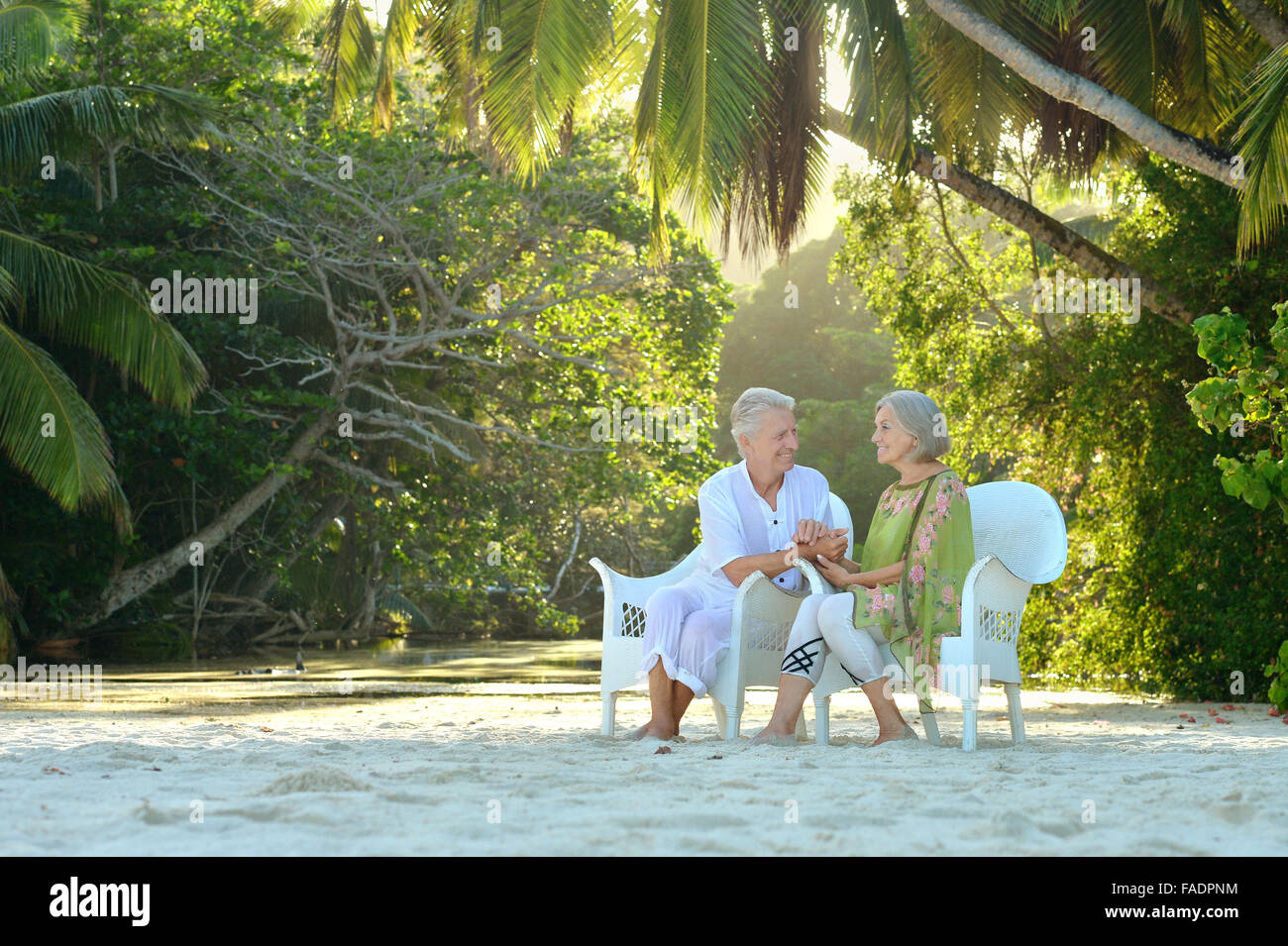 Elderly couple sitting on a beach Stock Photo - Alamy