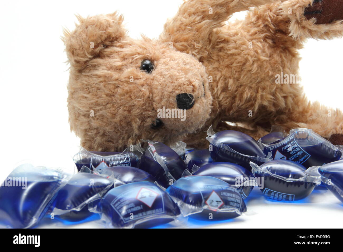 Liquid laundry detergent capsules surround a child's teddy bear UK