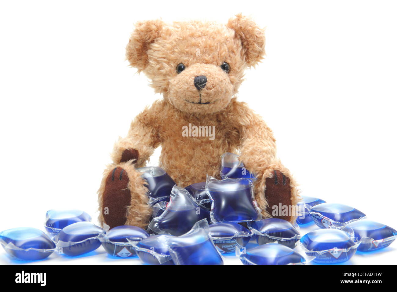 Liquid laundry detergent capsules surround a child's teddy bear UK