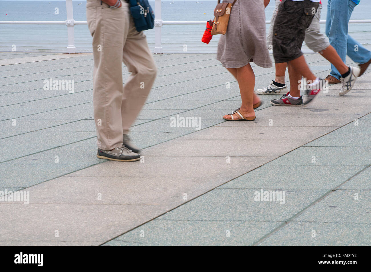 People's legs walking along the promenade. Gijon, Asturias, Spain. Stock Photo