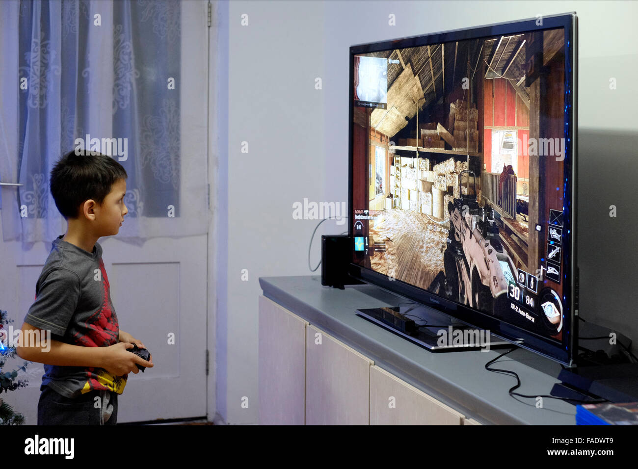 young boy playing video game on big flat screen tv in england uk Stock Photo