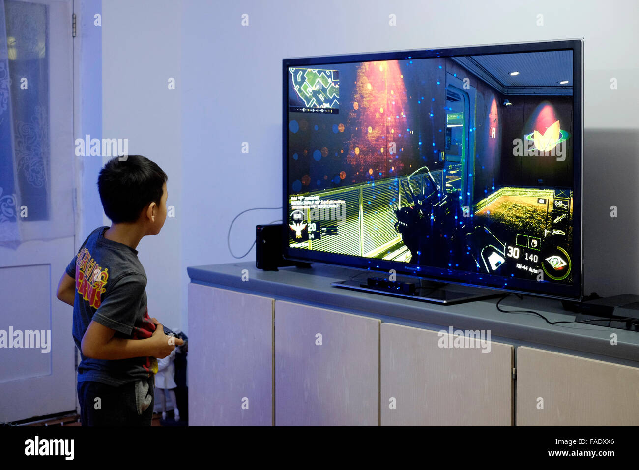 young boy playing video game on big flat screen tv in ... young boy playing vi