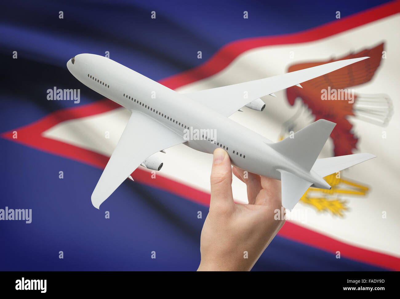 Airplane in hand with national flag on background - American Samoa Stock Photo