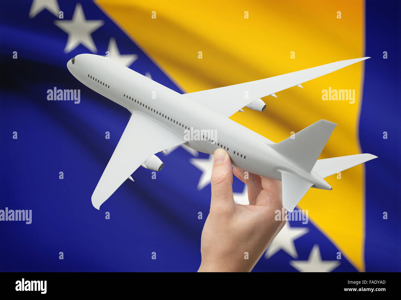 Airplane in hand with national flag on background - Bosnia and Herzegovina Stock Photo