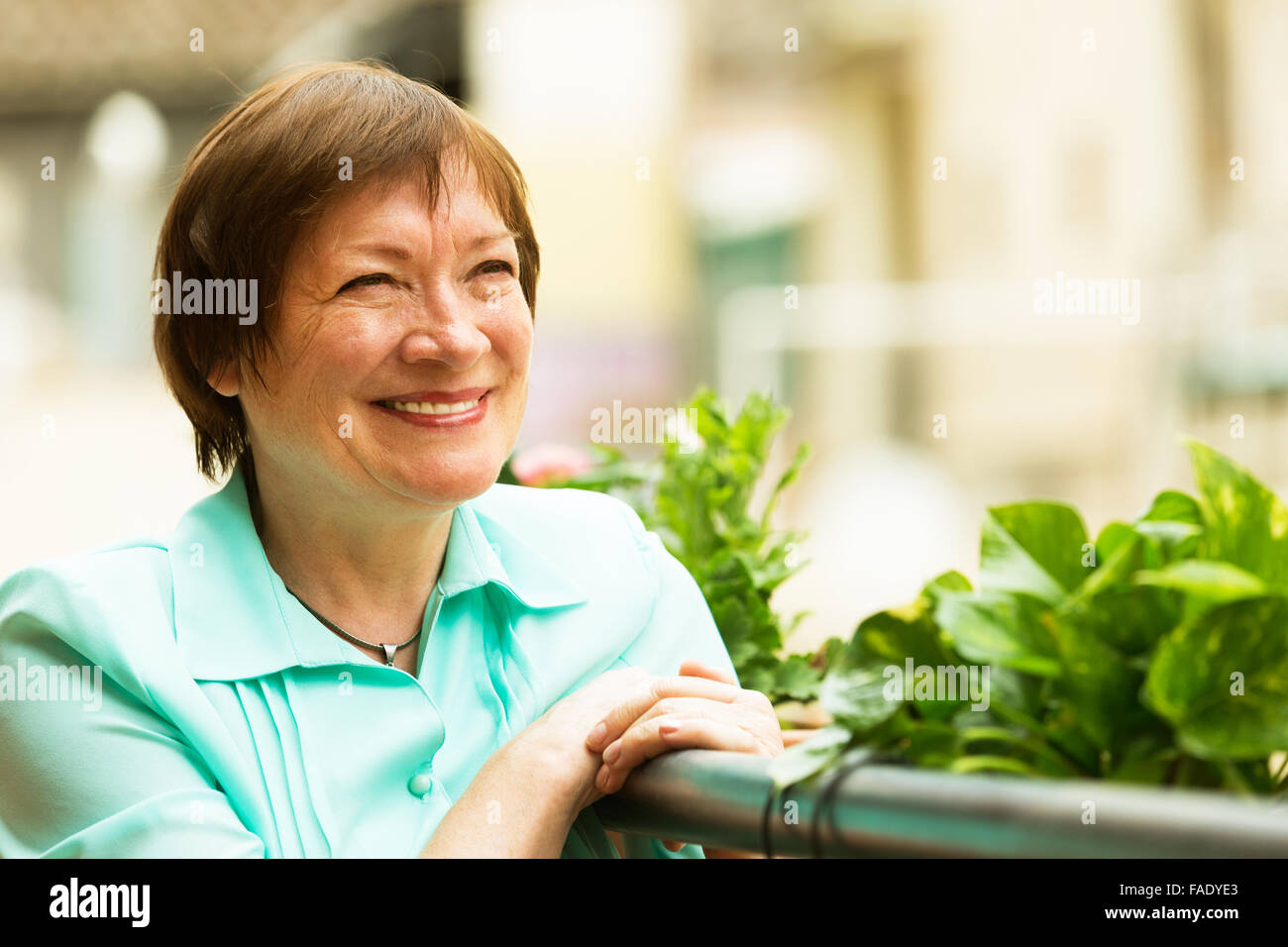 Female Pensioner Resting At Balcony With Flowers And Smiling Stock 