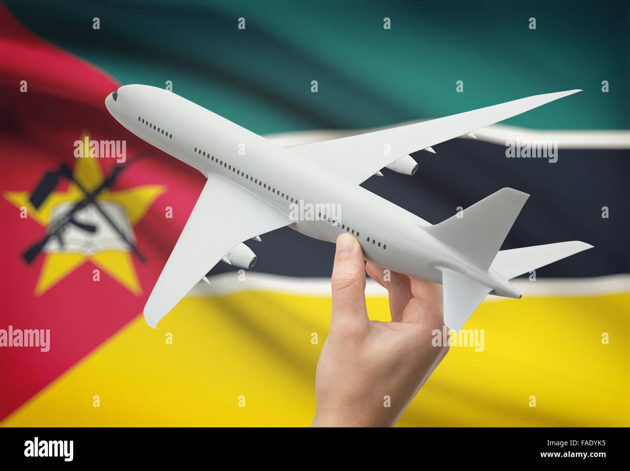 Airplane in hand with national flag on background - Mozambique Stock Photo