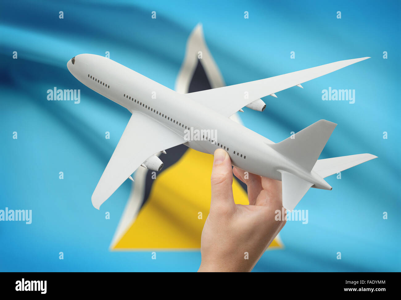 Airplane in hand with national flag on background - Saint Lucia Stock Photo