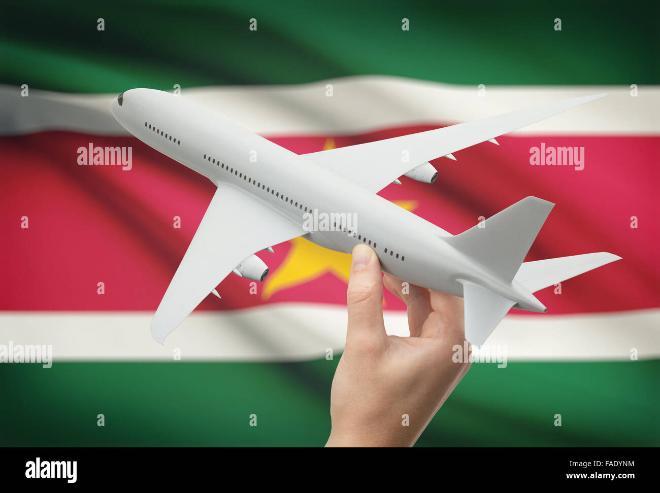 Airplane in hand with national flag on background - Suriname Stock Photo