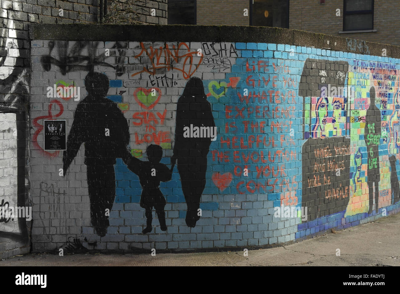 Multicoloured brick wall with life captions, black stencils man woman
