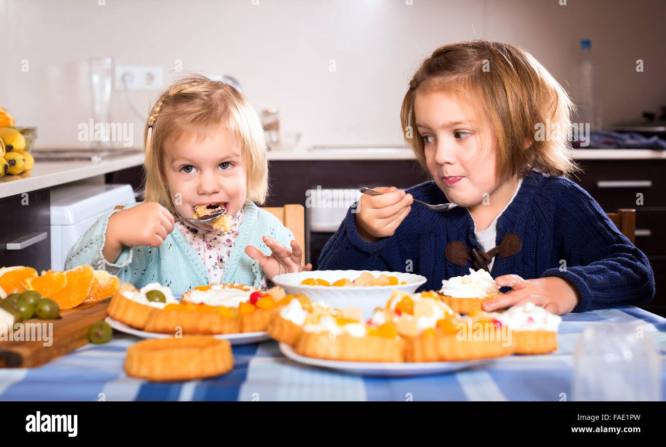 Young girls eating delicious cakes with cream with spoons in the