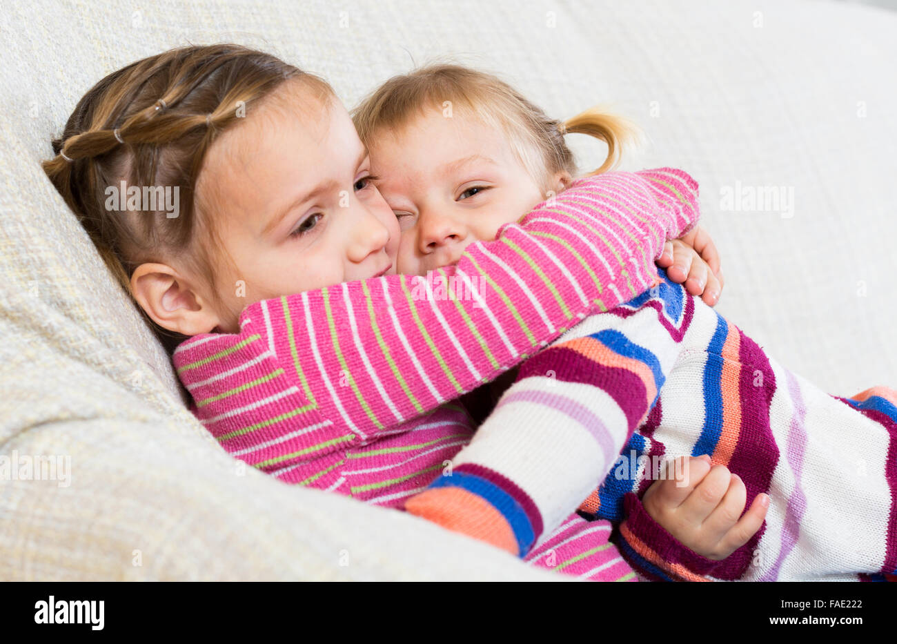 Two small girls embracing and laughing indoors Stock Photo - Alamy