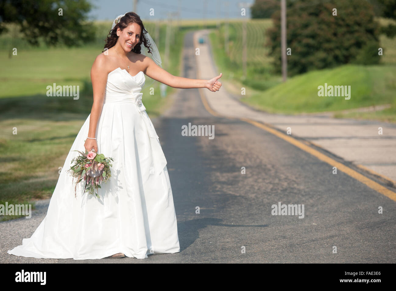 Bride hitching a ride in her wedding dress Stock Photo