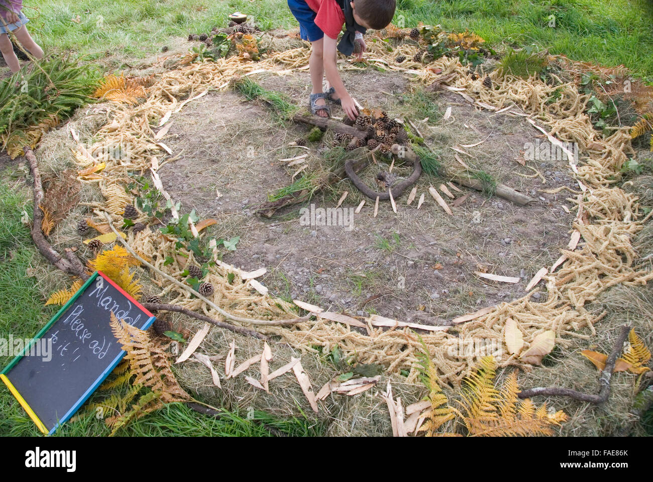 CHEPSTOW, WALES - July 2014: Boy adding to a Mandala circle created with natural items on 31 July at the Green Gathering Festiva Stock Photo