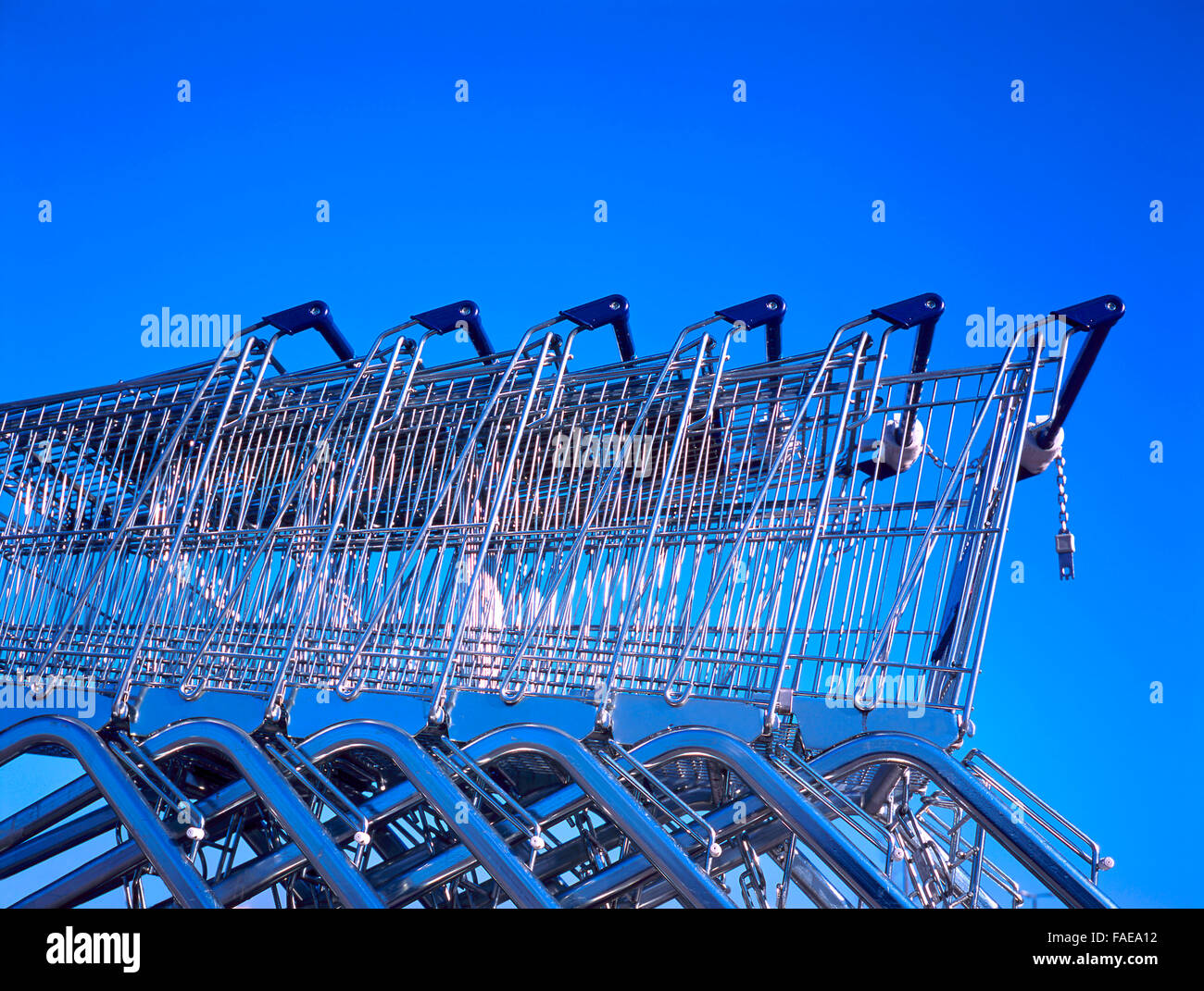 Shopping carts in row outside a supermarket against a clear blue sky. No brand names on it Stock Photo