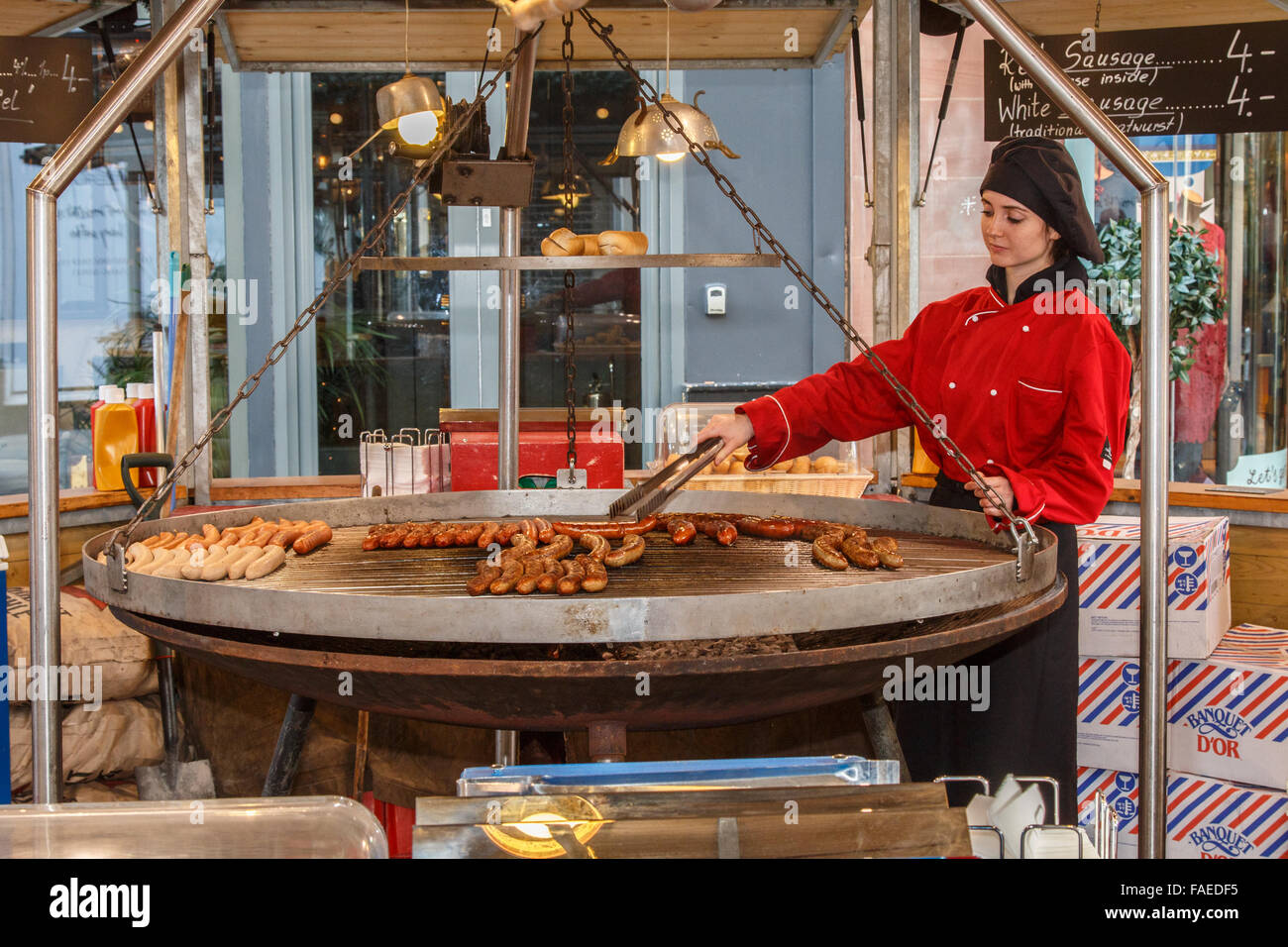 German sausages cooking on a huge swinging grill at the Manchester  Christmas market Stock Photo - Alamy