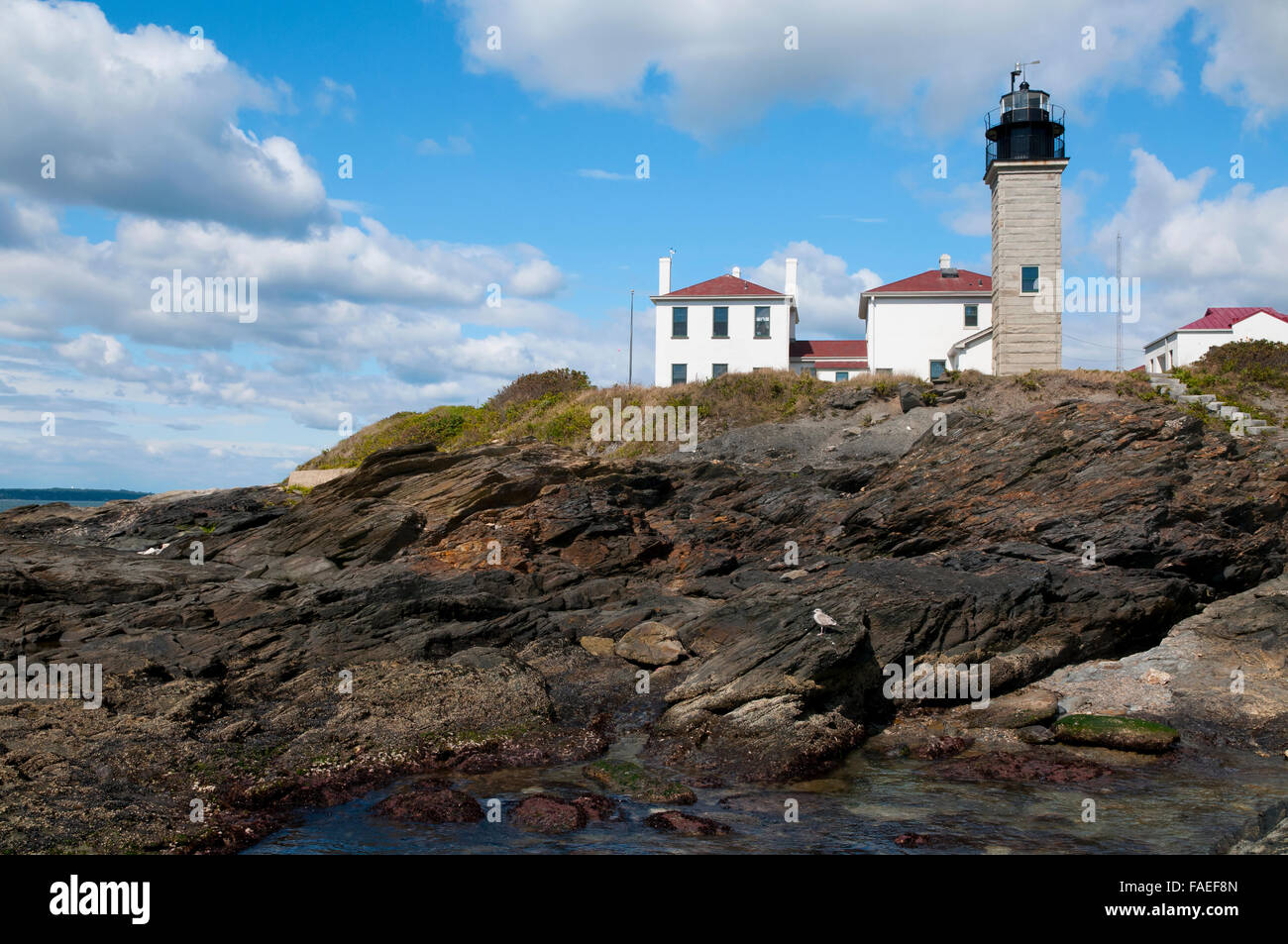 Beavertail lighthouse with its Colonial stone architecture guarding atop unique rock formations, is a favorite Rhode Island attraction near Newport. Stock Photo