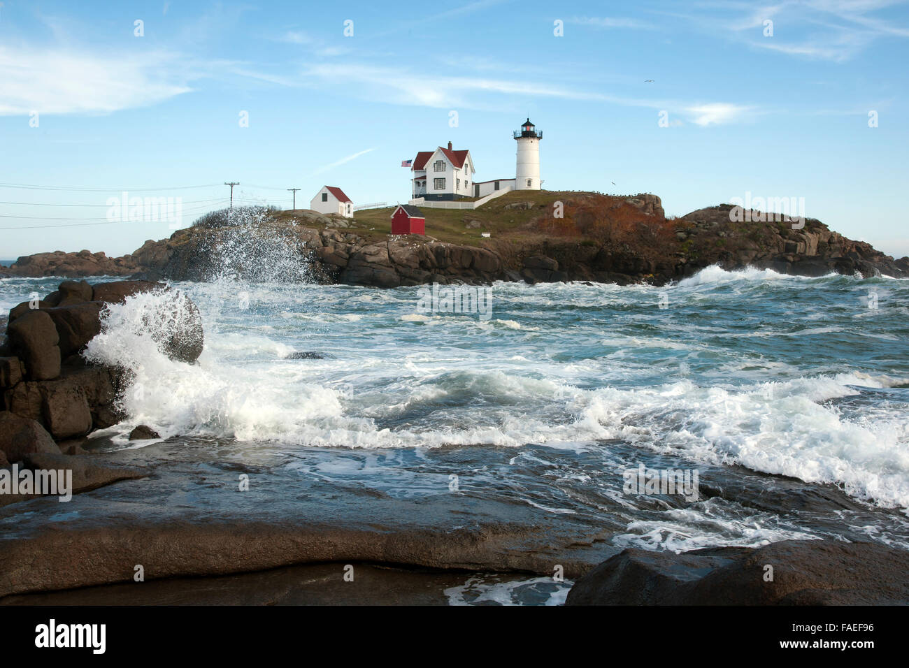 High tide surrounds the nubble island of Cape Neddick lighthouse in southern Maine as waves break over rocky coast. Stock Photo