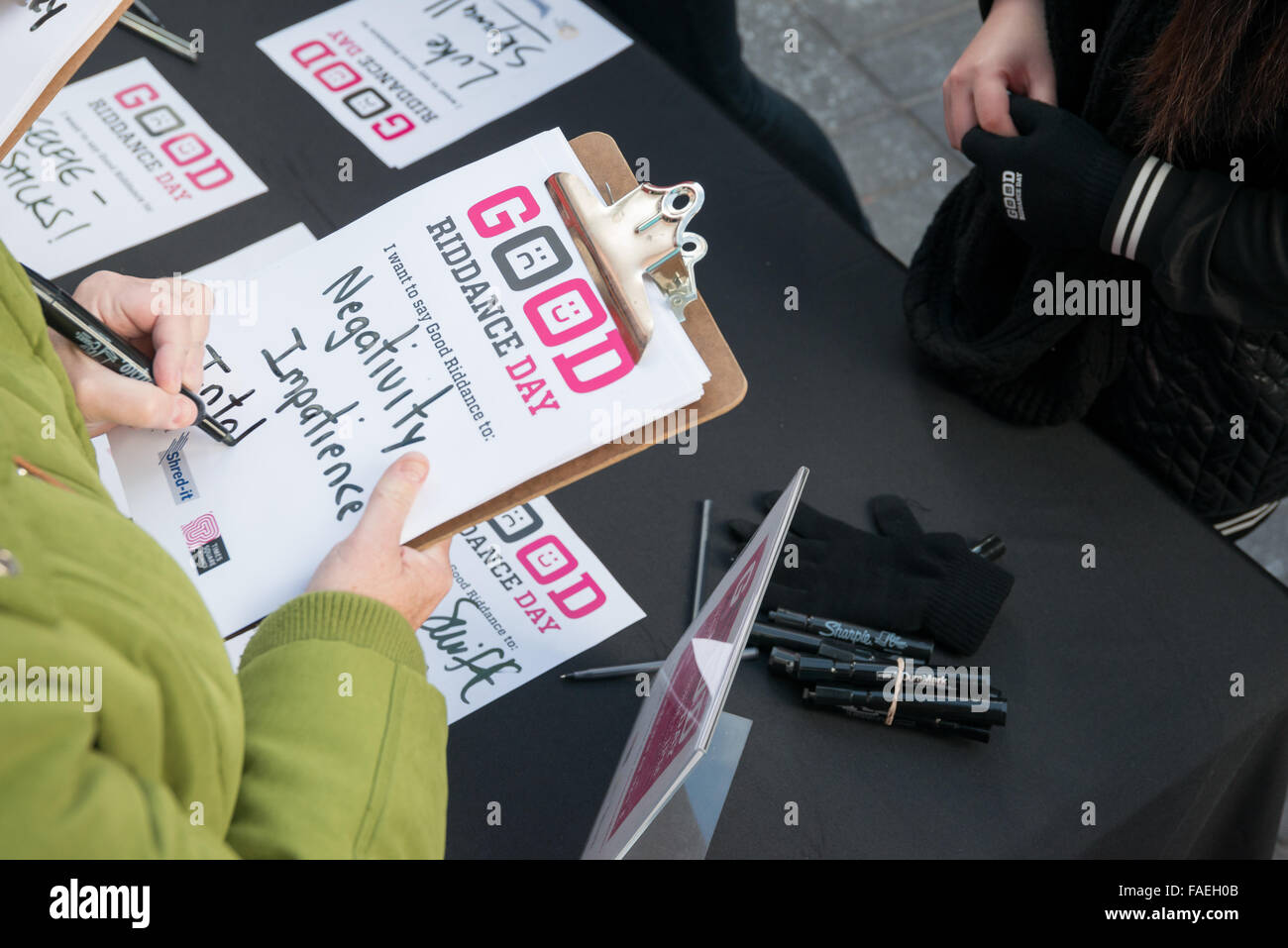 New York, USA. 28th Dec, 2015. A participant from the public writes a 'misfortune' from 2015 on a piece of paper that she will place into the shredder. In advance of the New Year, Times Square Alliance hosted the ninth rendition of its annual 'Good Riddance Day,' where the public is invited to symbolically shred letters, photos, or written messages conveying unpleasant memories from 2015. Hosted by media personality Alison Hagendorf and featuring brief comments by Times Square Alliance President Tim Tompkins, the event, sponsored by the document destruction company Shred-It, drew hundreds of p Stock Photo