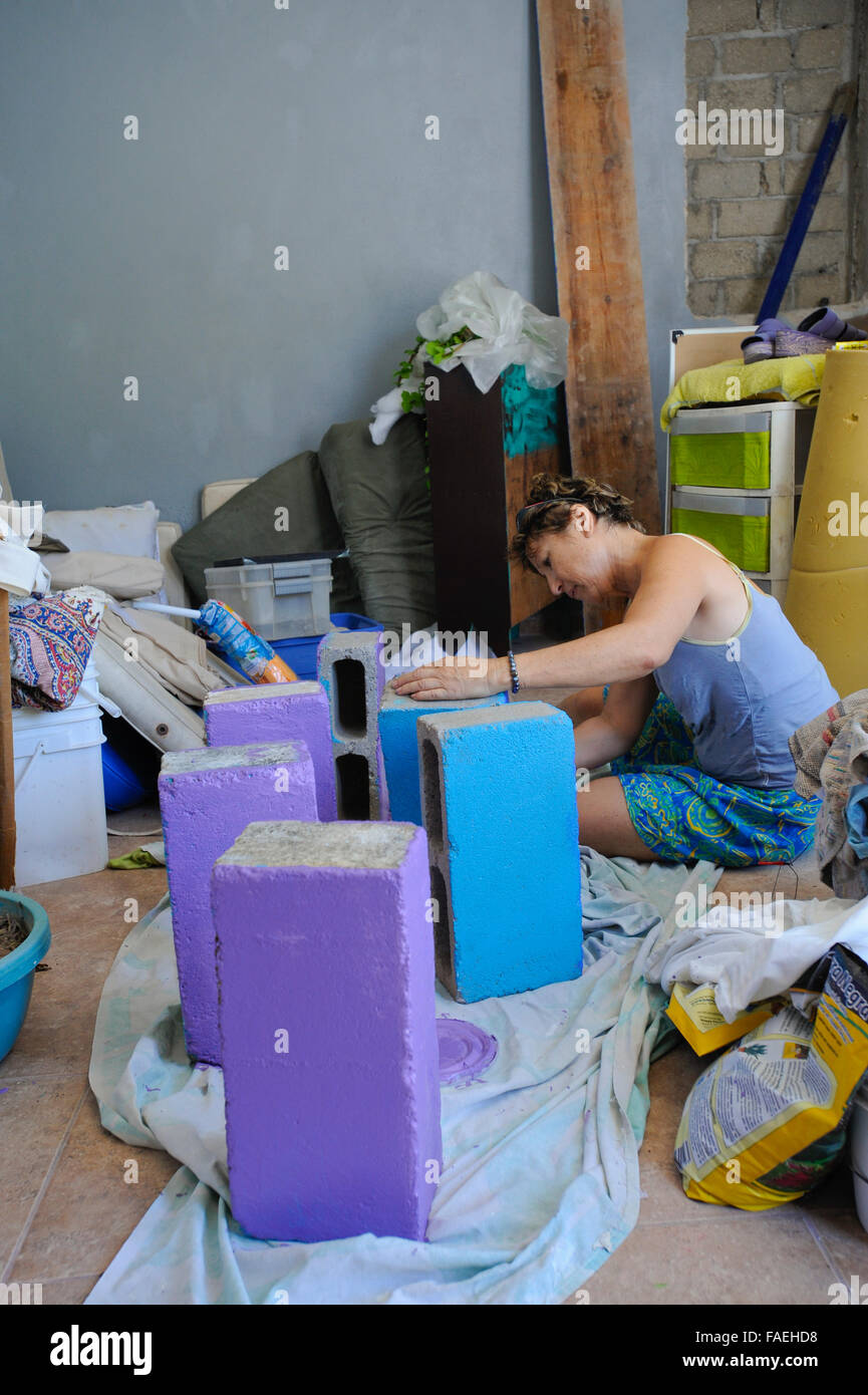 Woman painting cement blocks for shelves, Acapulco, Mexico Stock Photo