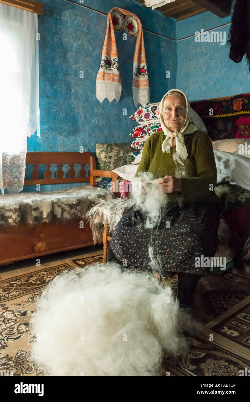 elderly woman while spinning wool at her home Stock Photo