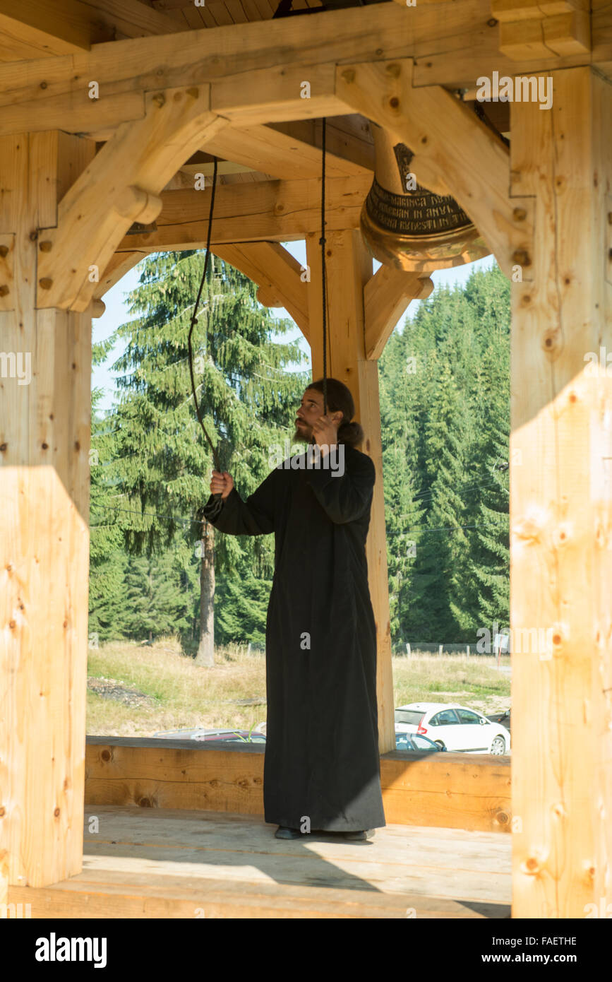 a young priest rings a bell Stock Photo
