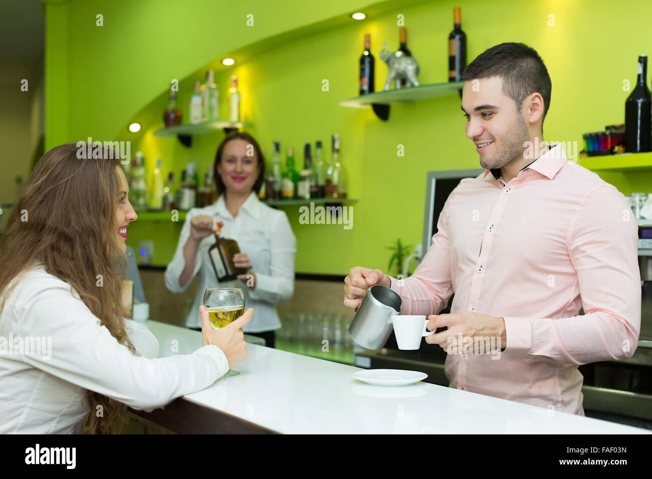 Positive bar emplyees serving clients at counter Stock Photo