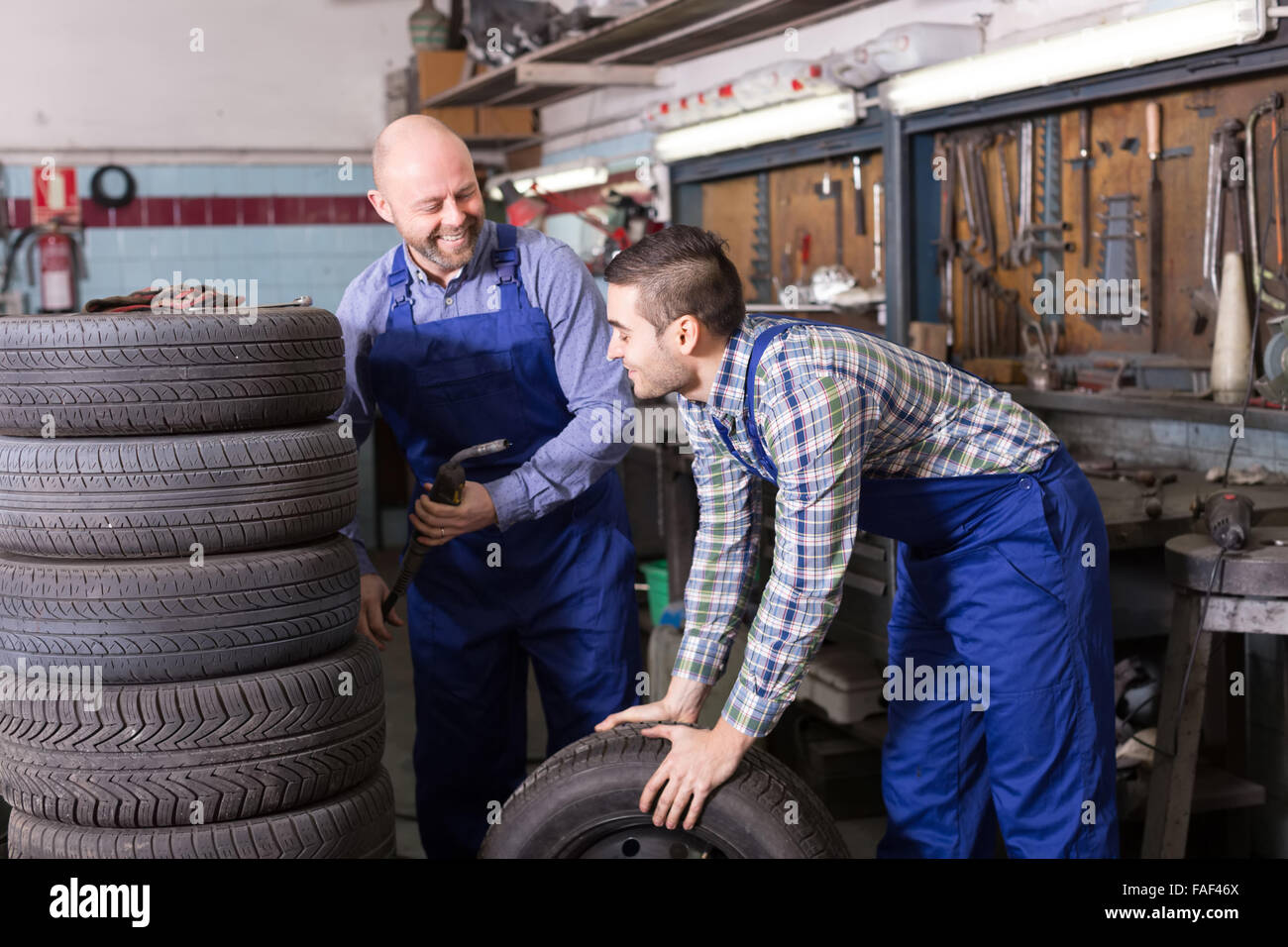 happy car mechanics in coveralls working at carshop Stock Photo
