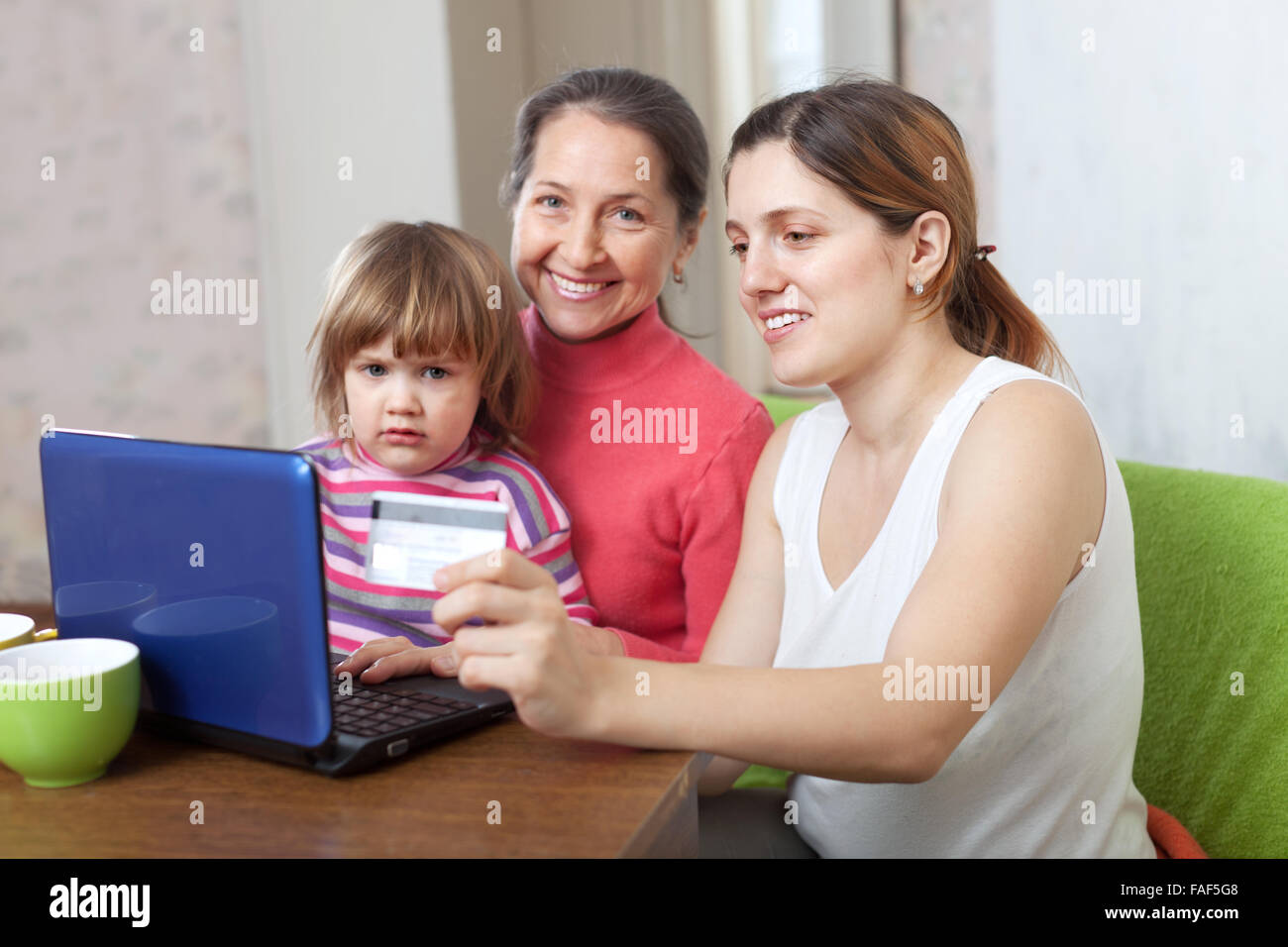 Happy family of three generations doing shopping in internet with credit card at home Stock Photo