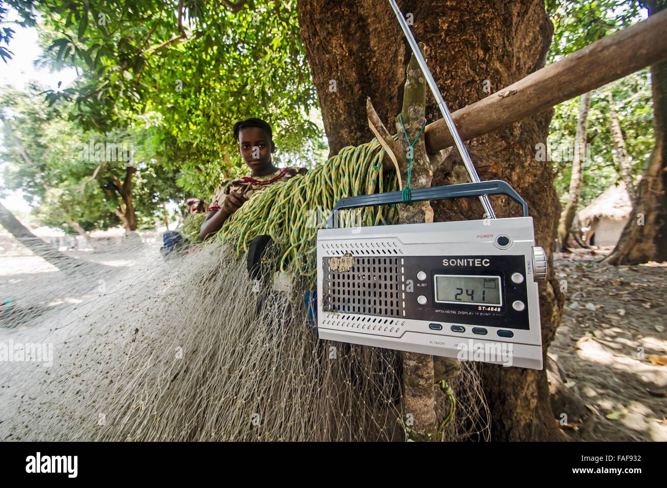 Listening to the radio while mending fishing nets in southern Sierra Leone  Stock Photo - Alamy