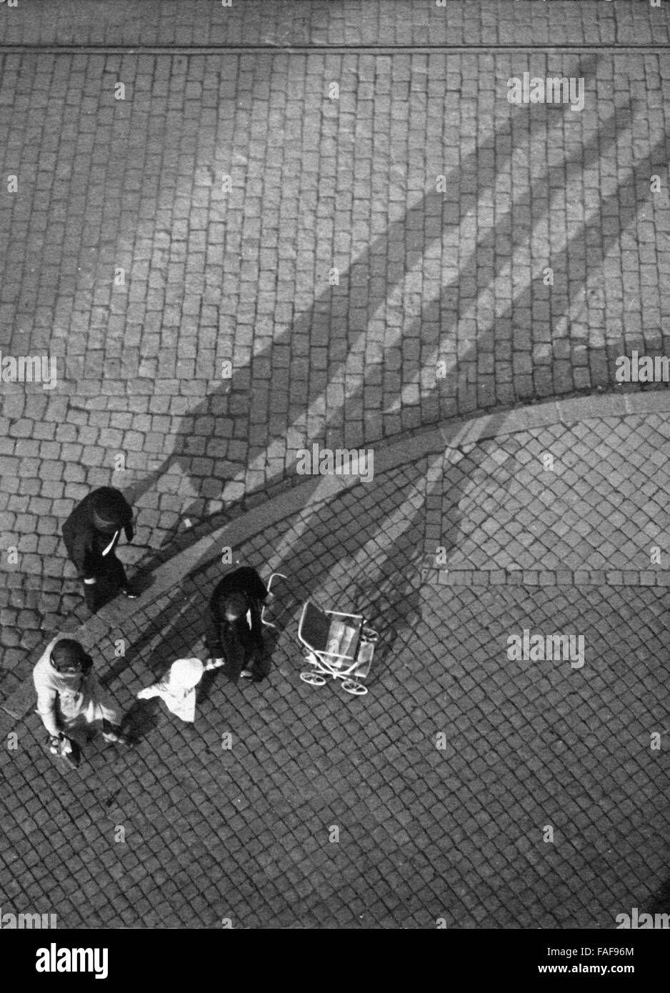 Menschen werfen einen Schatten auf das Kopfsteinpflaster einer Straße in Köln, Deutschland 1930er Jahre. People and their shadows on the cobblestone of a street at Cologne, Germany 1930s. Stock Photo