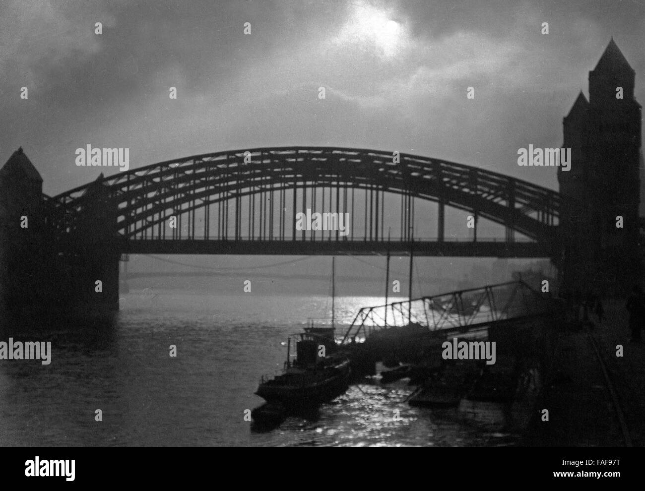 Die Hohenzollernbrücke in Köln im Gegenlicht, Deutschland 1920er Jahre. Hohenzollernbruecke bridge at Cologne in backlight, Germany 1920s. Stock Photo