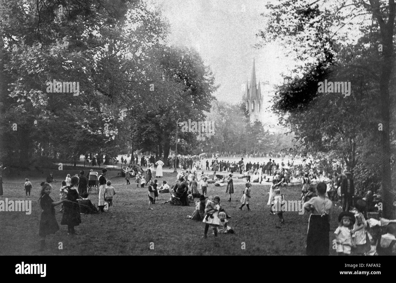 Kinder spielen im Volksgarten in der Südstadt von Köln, mit Blick auf die Kirche St. Paul, Deutschland 1910er Jahre. Children playing at Volksgarten park in the sout hpart of the city of Cologne, with view to St. Paul's church, Germany 1910s. Stock Photo