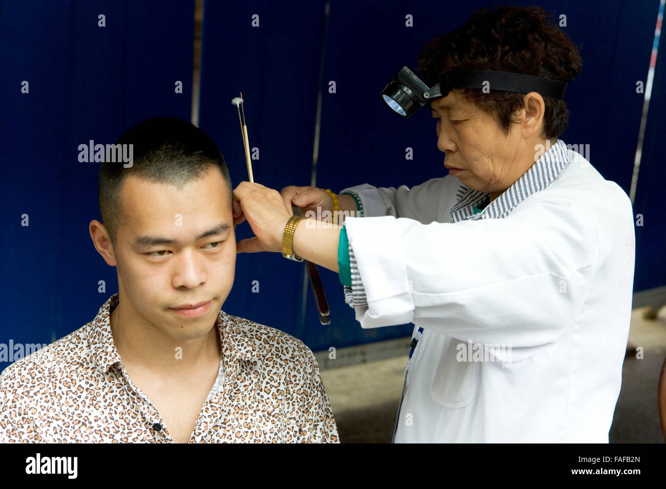 Patient having his ears cleaned by Chinese doctor. China. Stock Photo