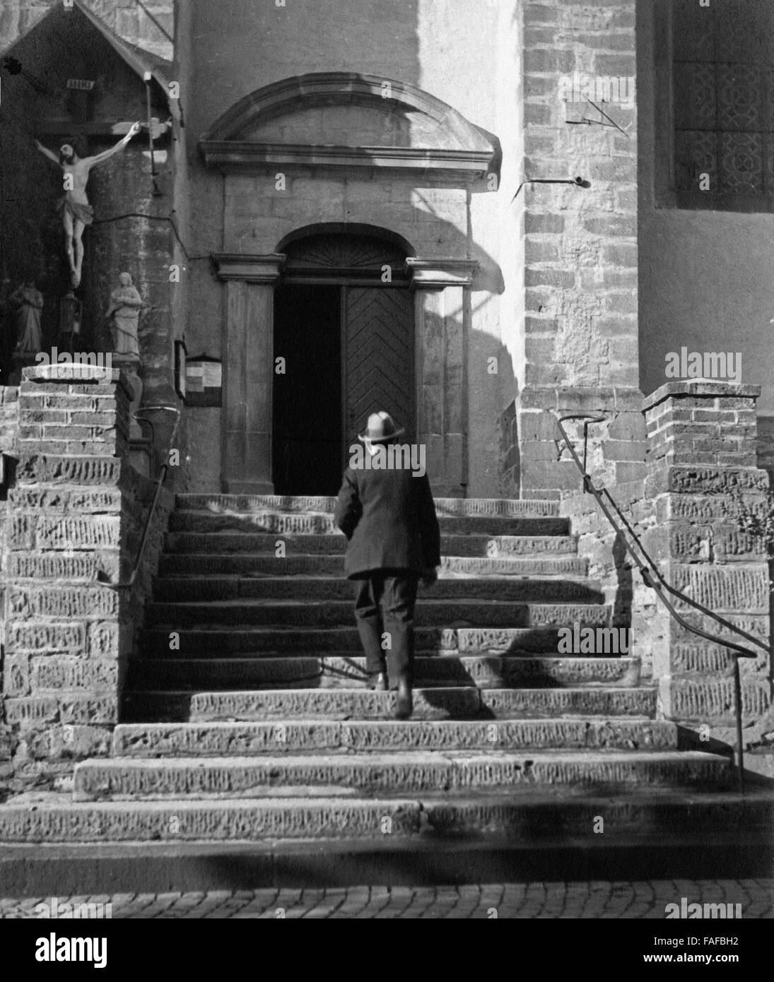 Ein Mann auf der Treppe zur Pfarrkirche St. Clemens in Heimbach in der Eifel, Deutschland 1930er Jahre. A man on the entrance steps to St. Clemens's church at Heimbach in Eifel area, Germany 1930s. Stock Photo