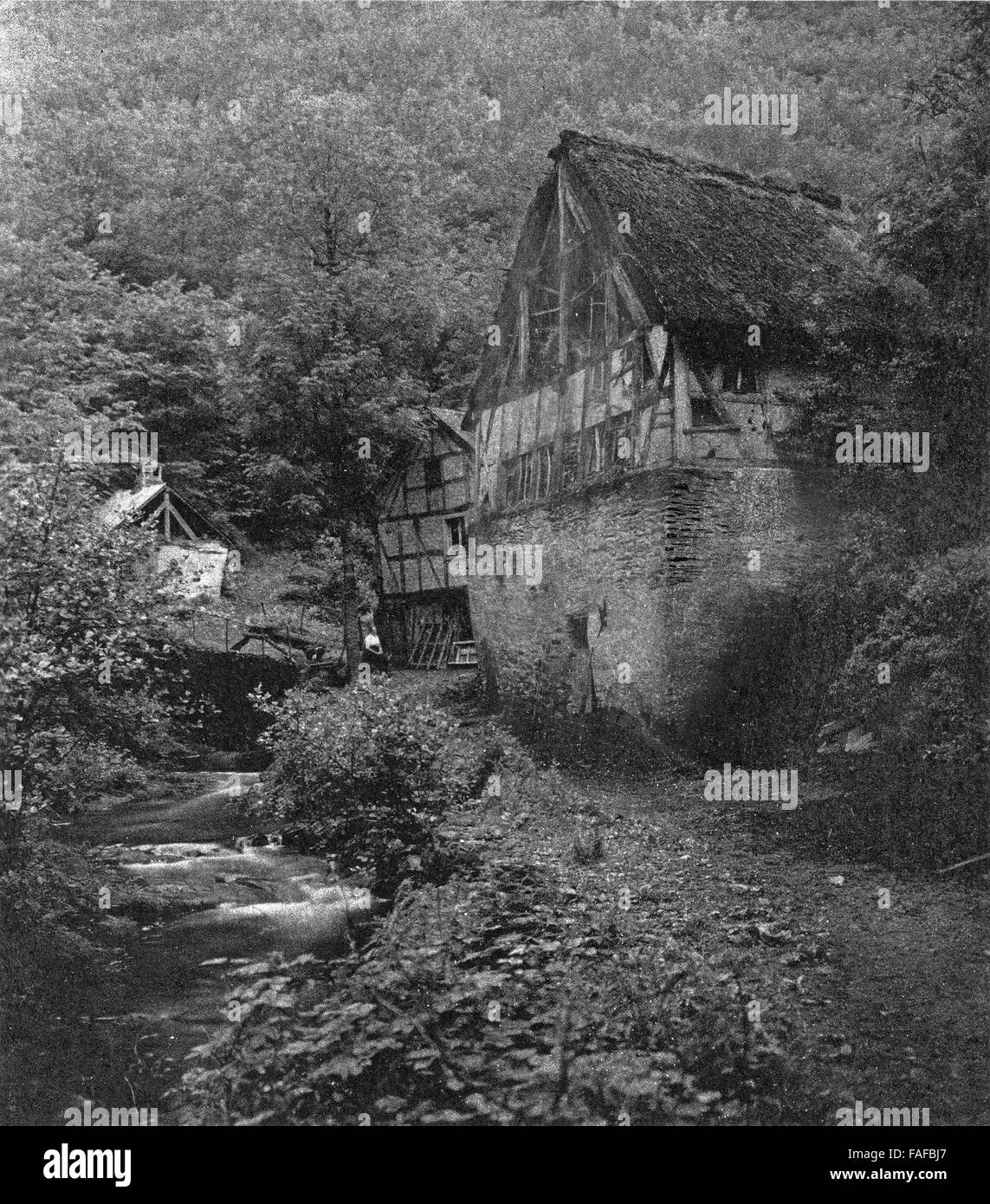 Idyllische Fachwerkmühle an einem kleinen Flußlauf, Deutschland 1920er Jahre. Timbered house with a mill at a small river, Germany 1930s. Stock Photo