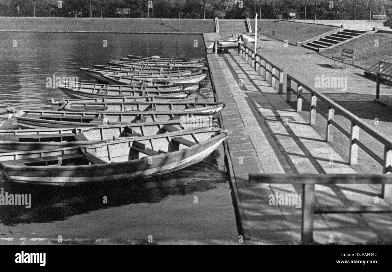 Boote am Anlegesteg am See im Blücherpark in Köln Bilderstöckchen, Deutschland 1930er Jahre. Rowing boats at a boardwalk on a lake at Bluecherpark gardens at Cologne Bilderstoeckchen, Germany 1930s. Stock Photo