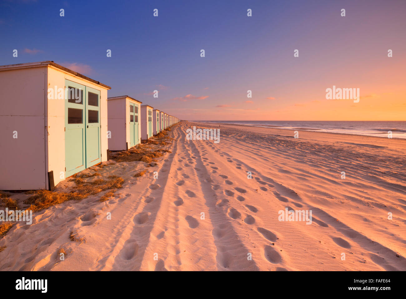 A row of beach huts on a beach on the island of Texel in The Netherlands. Photographed at sunset. Stock Photo