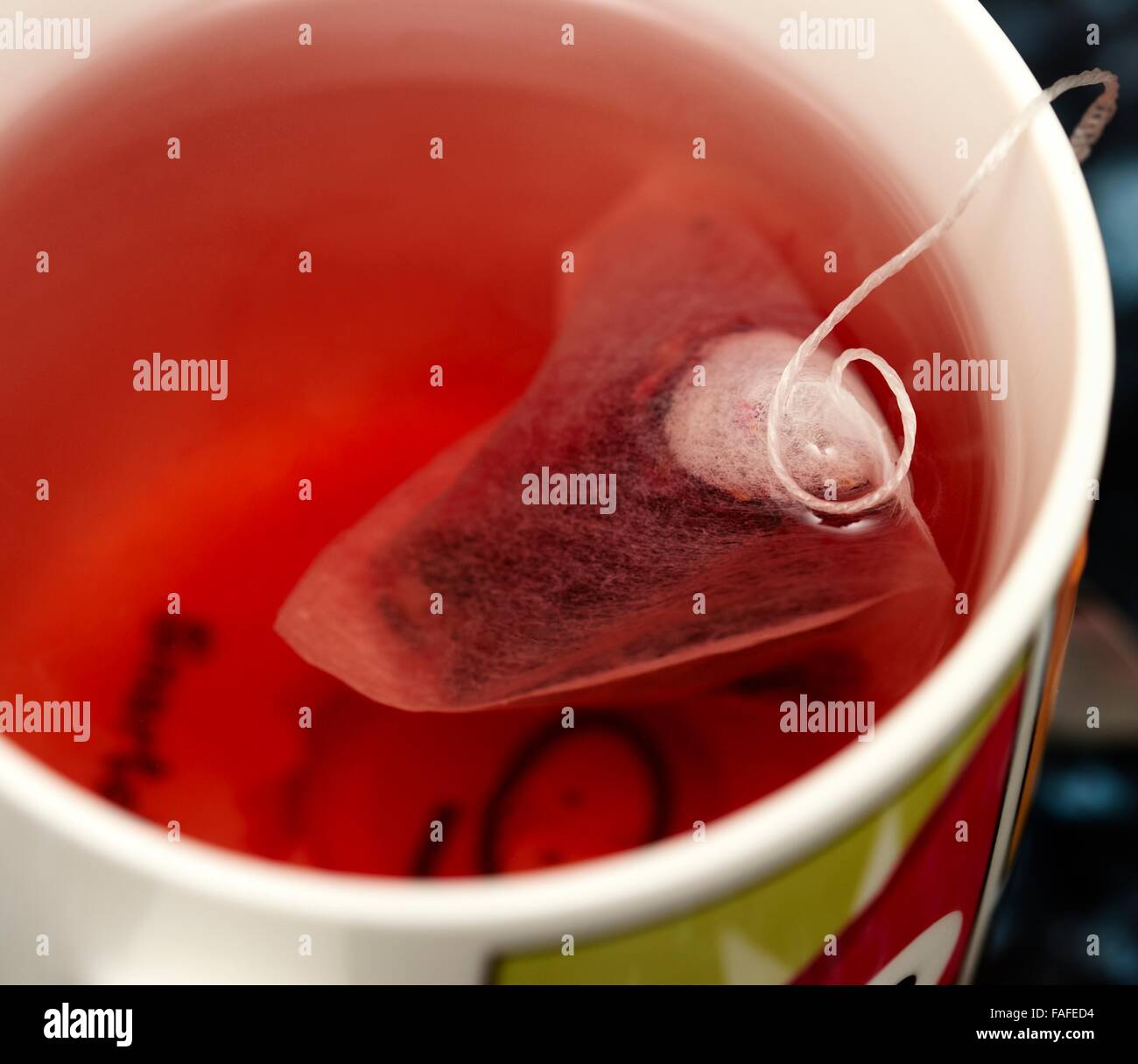 A red berry herbal infusion hot drink with a pyramid tea bag in a mug close up Stock Photo