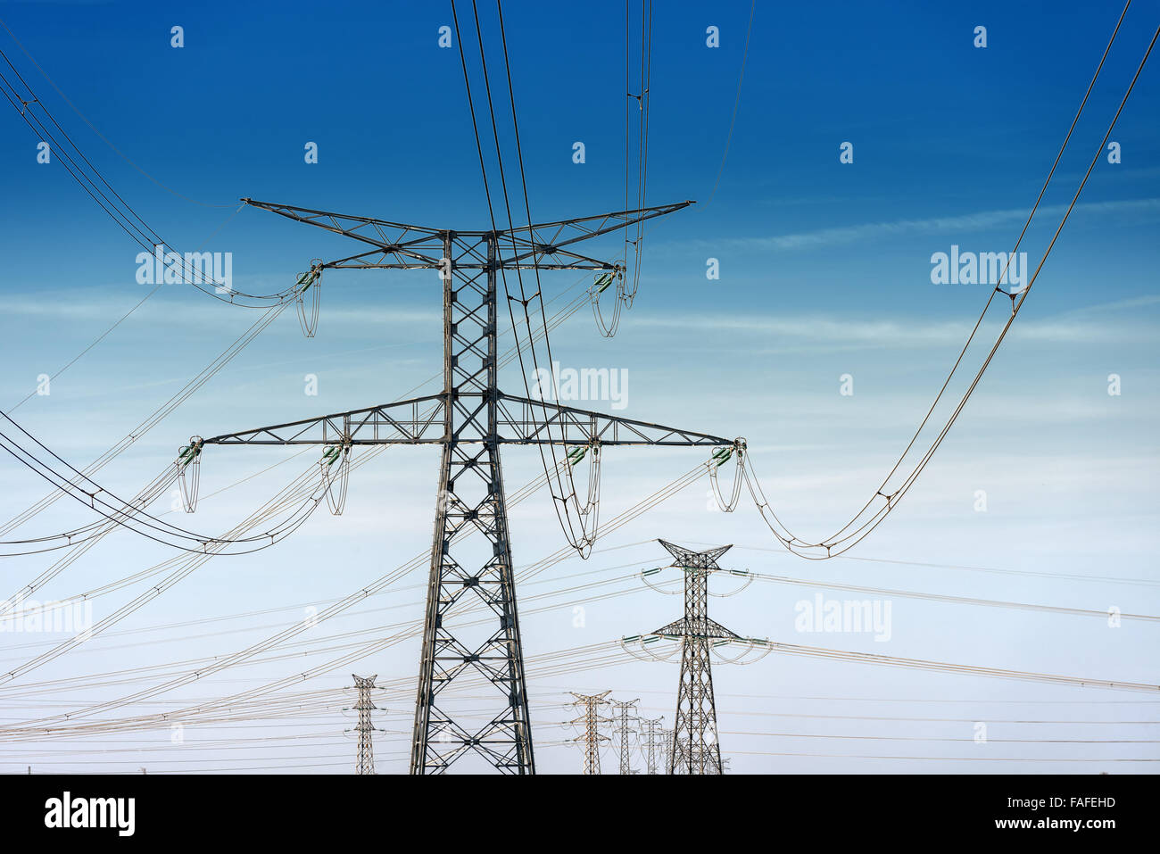 high voltage pylons on blue cloudy sky background Stock Photo - Alamy