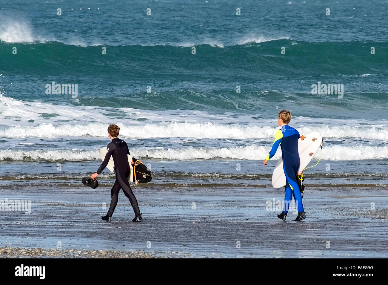 two young surfers heading for the waves at Holywell Bay in Cornwall, UK Stock Photo