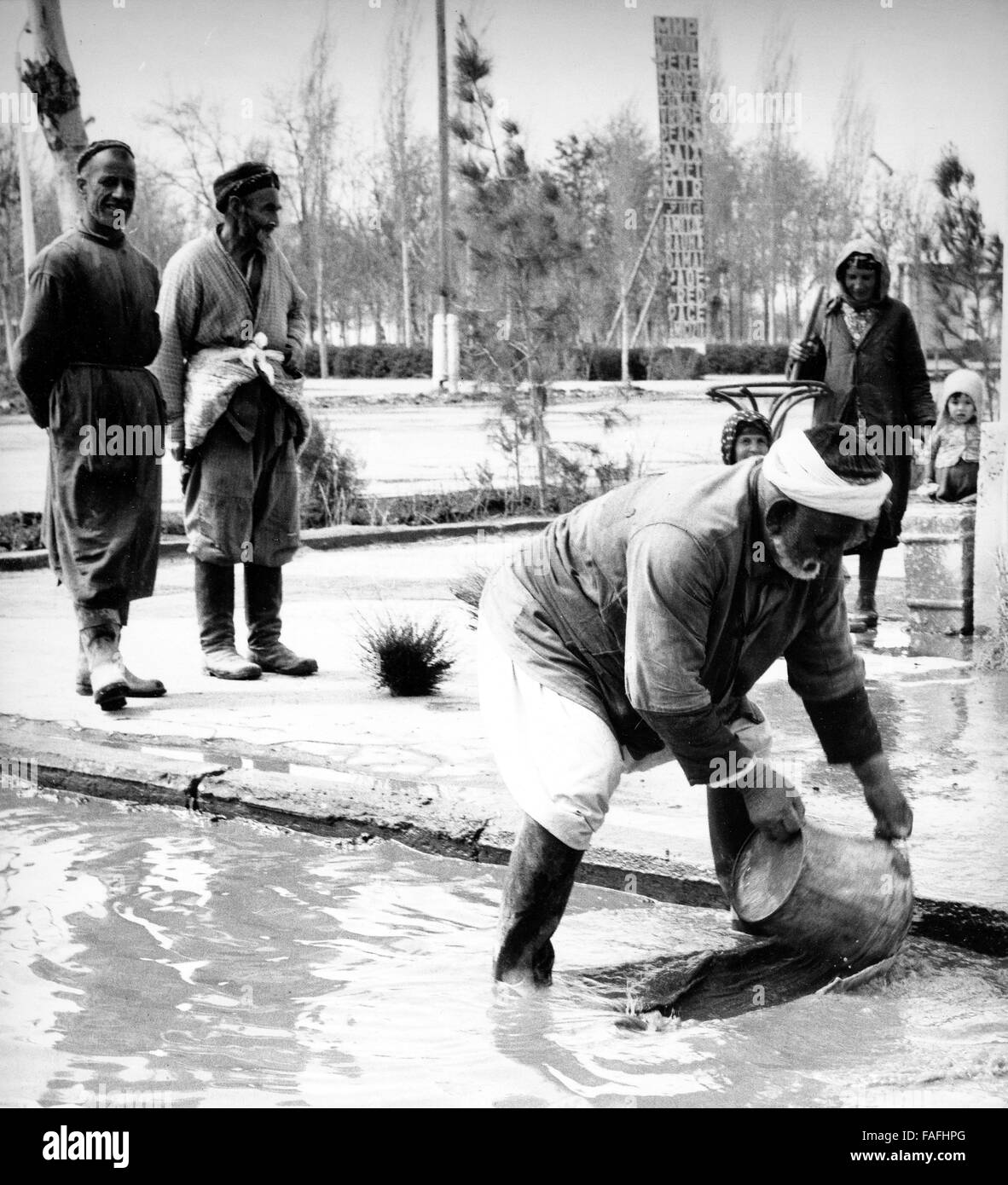 Ein Mann schöpft Wasser nach einem Regenguss in Buchara in Usbekistan, Sowjetunion, 1970er Jahre. A man scooping water after a downpour at Bukhara in Uzbekistan, Soviet Union, 1970s. Stock Photo