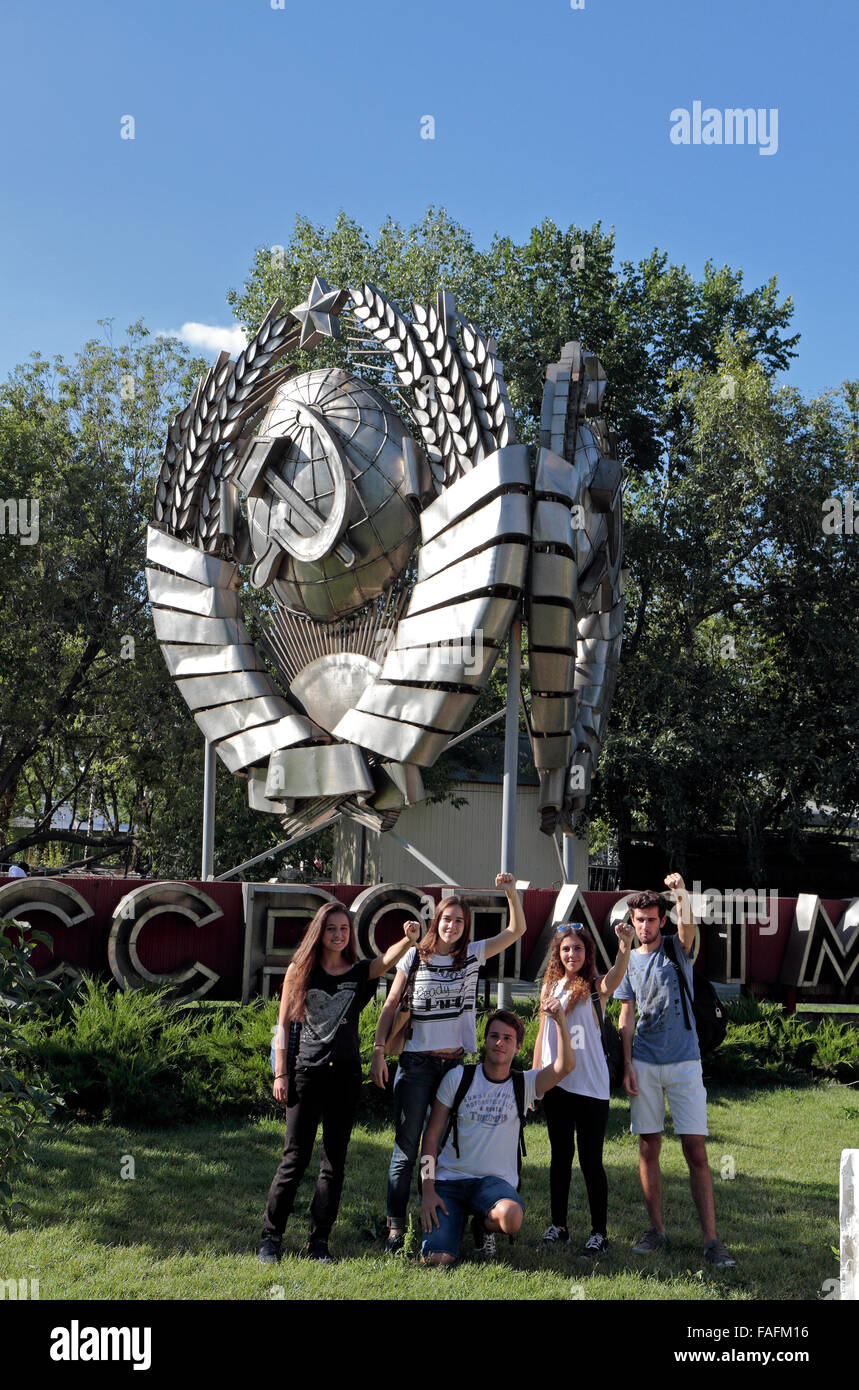 A group pose in front of an old CCCP hammer & sickle sign in the Fallen Monument Park (Muzeon Park of Arts), Moscow, Russia. Stock Photo