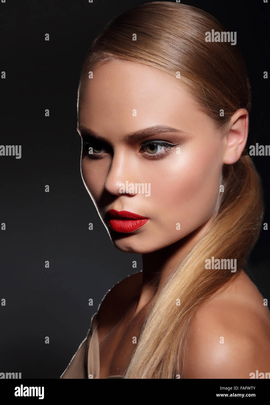 Young woman with straight hair and and red lips on dark background. Portrait. Stock Photo