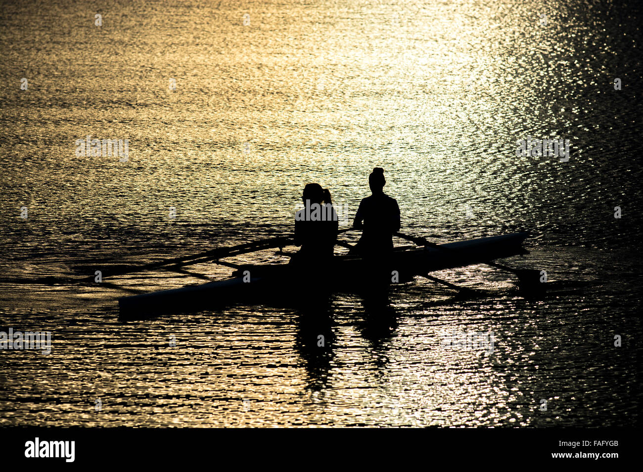 Female Rowers In A Double Scull On Sunset Lake Stock Photo