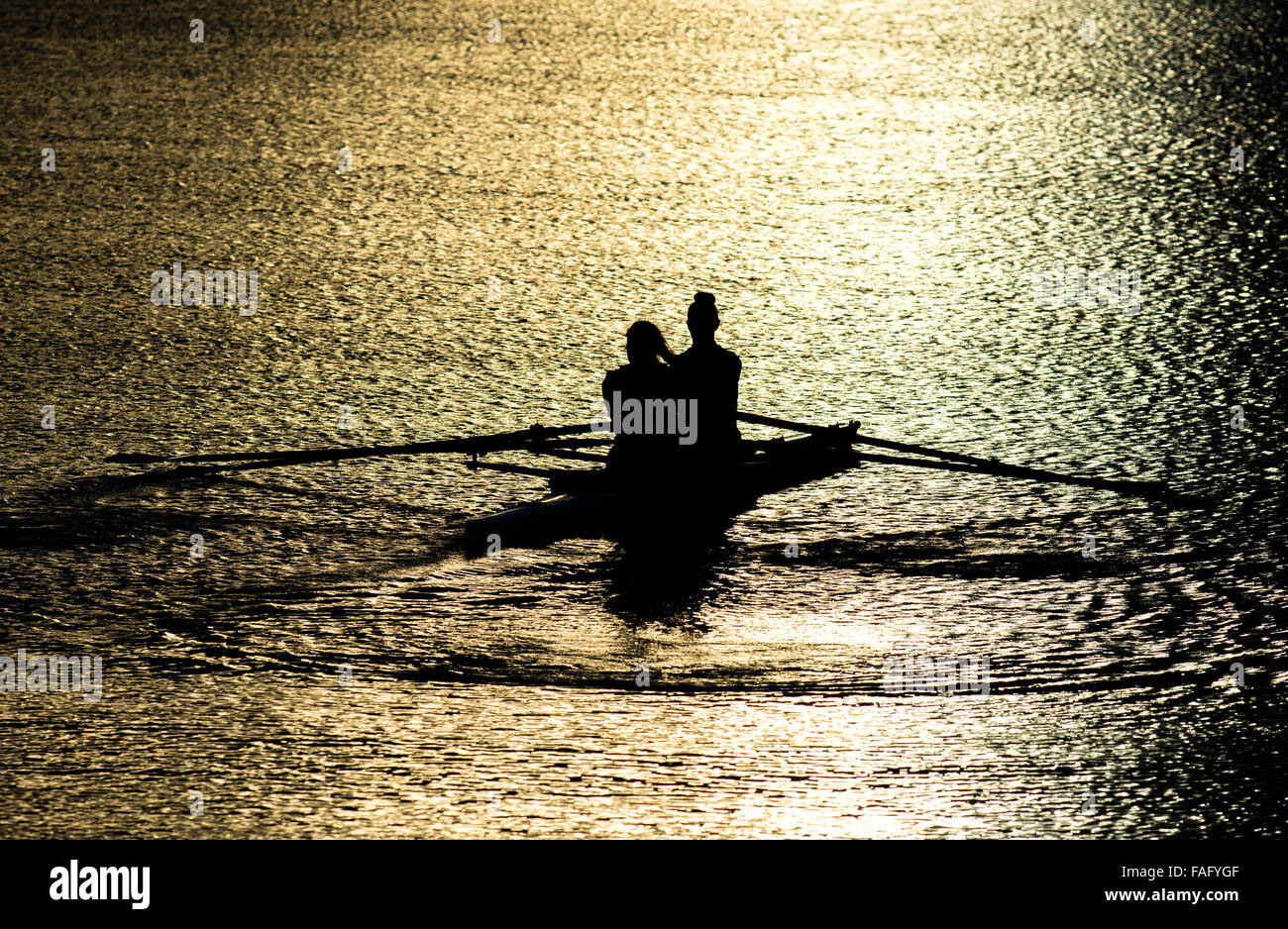Female Rowers In A Double Scull On Sunset Lake Stock Photo