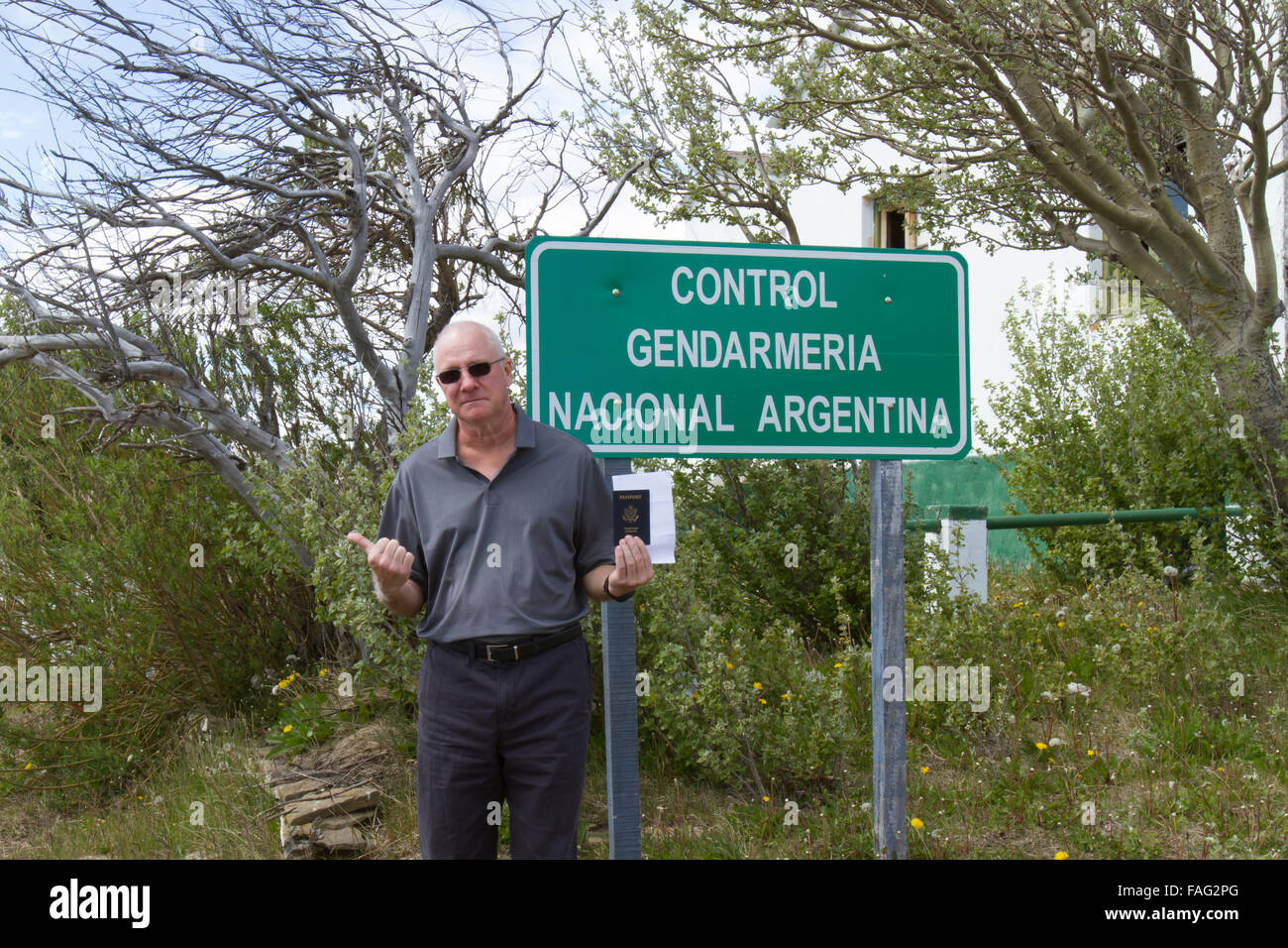 Senior man holding American passport with reciprocity papers hitchhiking at the Argentinian border. Stock Photo